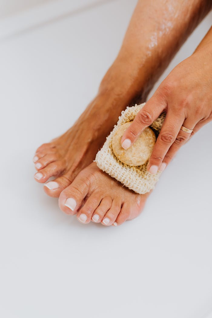 services-10 A close-up photo showing foot care using a loofah for exfoliation and maintenance.
